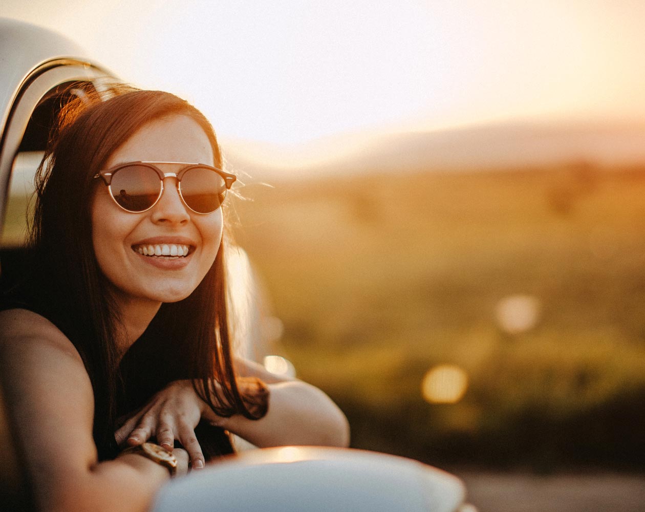 Smiling girl resting her arms on an open car window