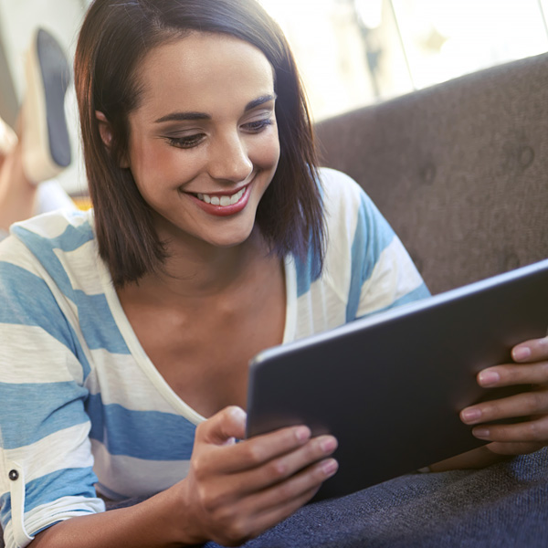 A woman laying down on the couch paying bills on Billpay