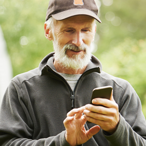 An older gentleman checking his notifications on his phone