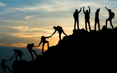 A group of people helping each other climb a mountain